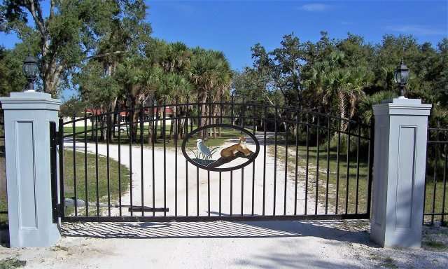 A gated driveway with trees in the background.