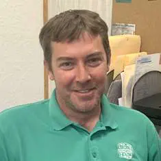 A man in green shirt smiling for the camera.
