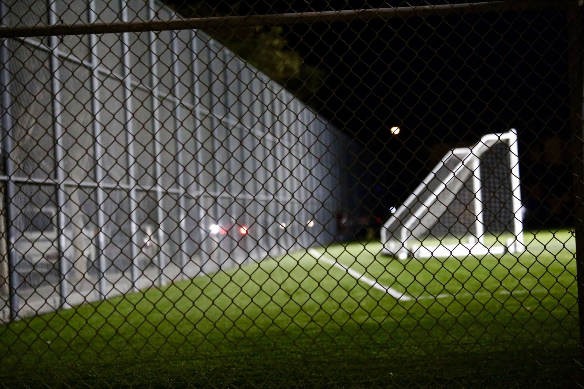 A soccer field with goal posts and lights at night.
