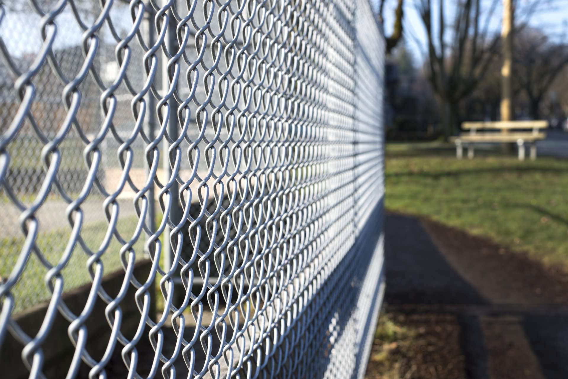 A chain link fence with grass in the background.
