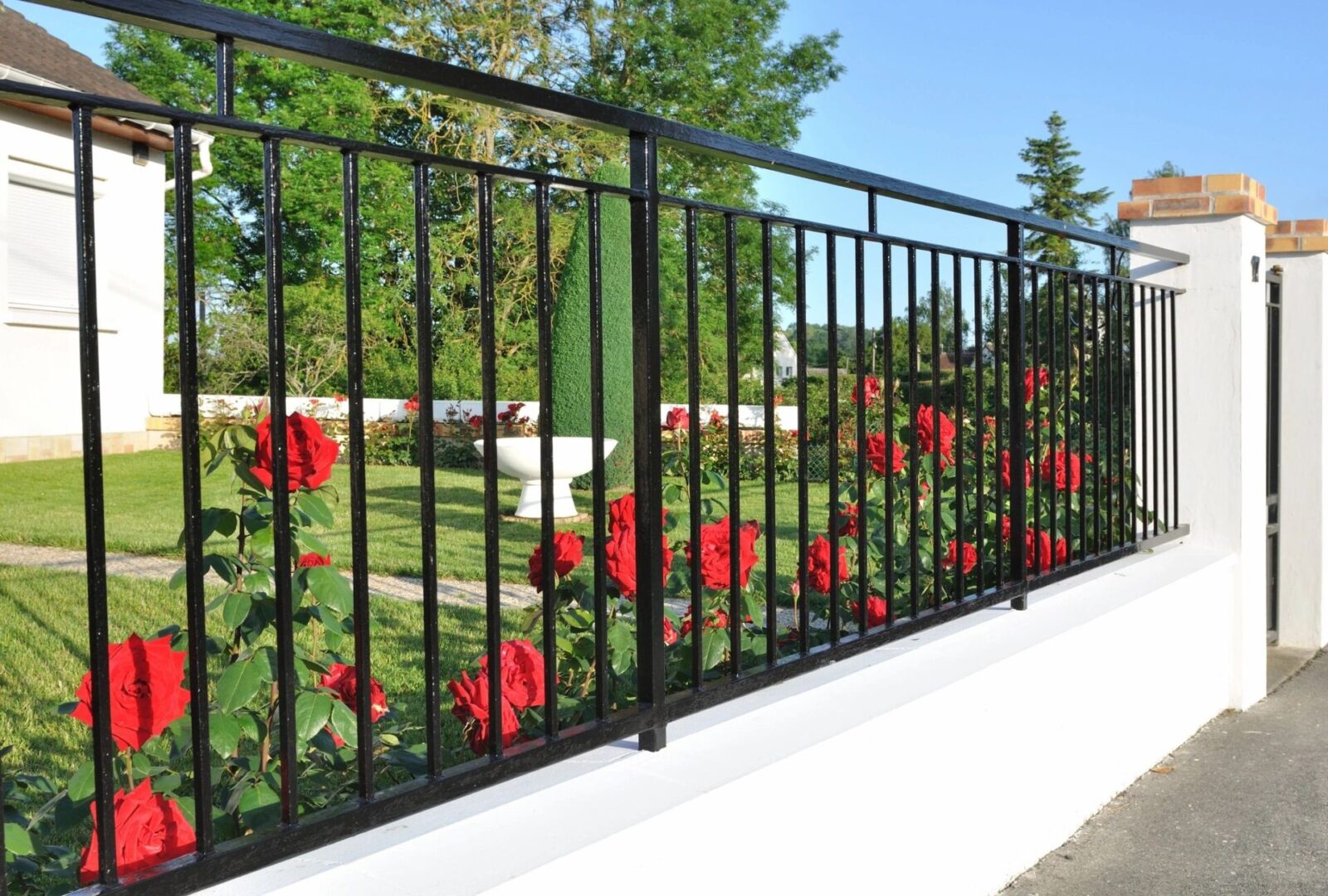 A black metal fence with red flowers on it.