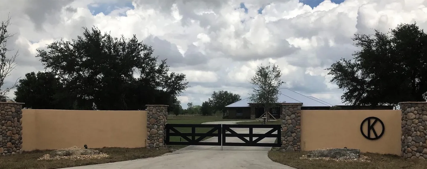 A driveway with two gates and stone walls.