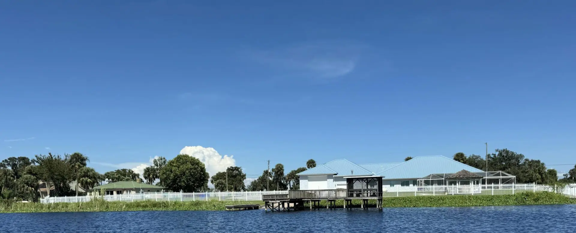 Lakefront home with dock and blue sky.