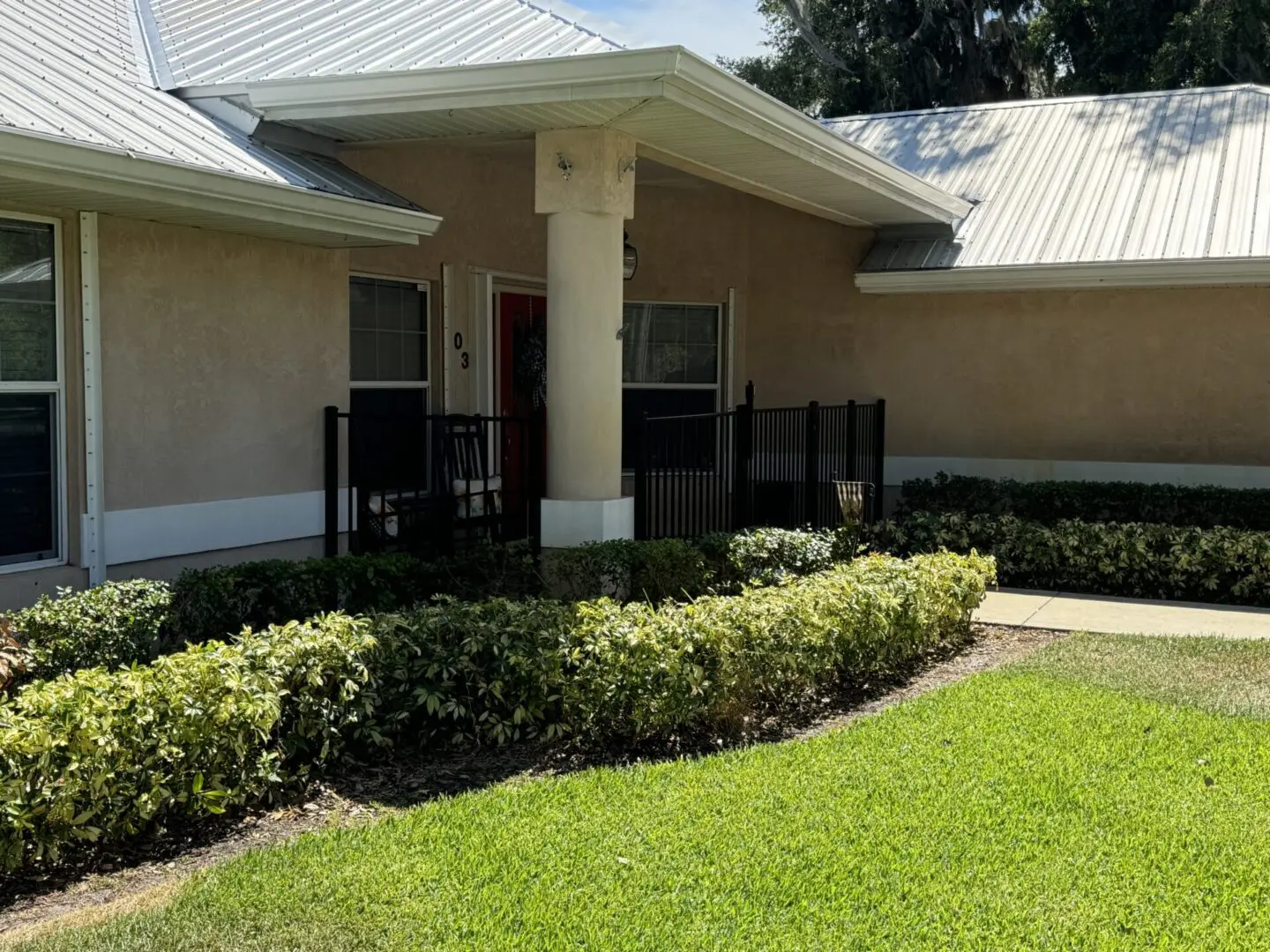 House entrance with porch and shrubs.