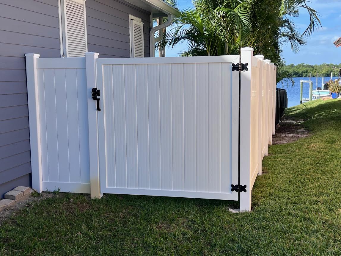 White vinyl fence with gate and black hinges.