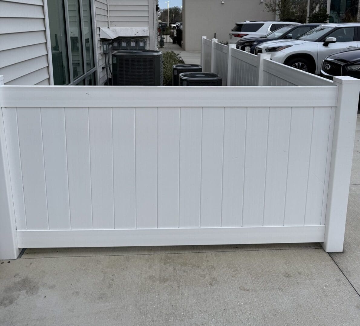 White vinyl fence concealing AC units.