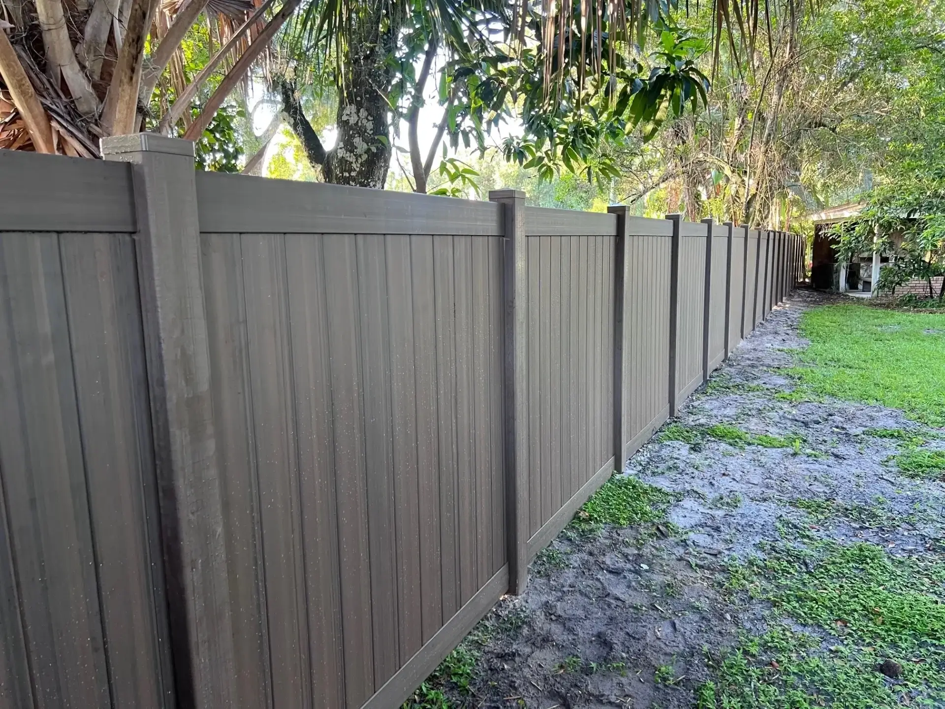 Long brown fence beside grassy area.