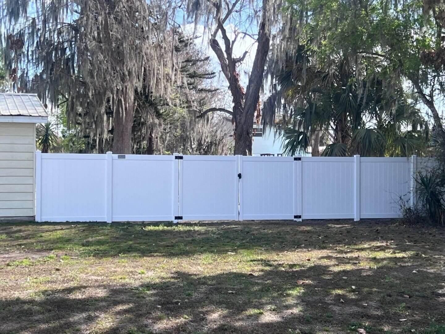 White fence beside trees and house.