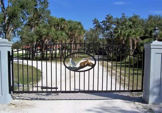 A gated driveway with trees in the background.