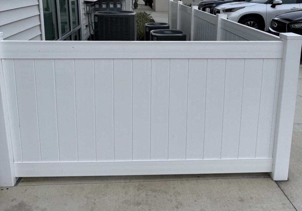 White vinyl fence concealing AC units.