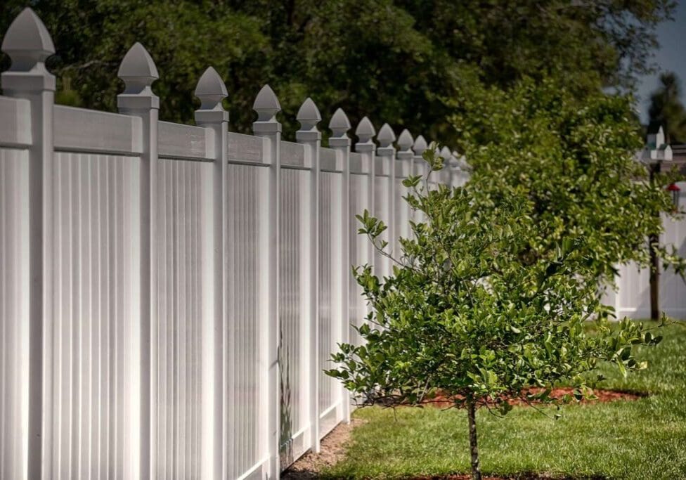 A white fence with trees in the background